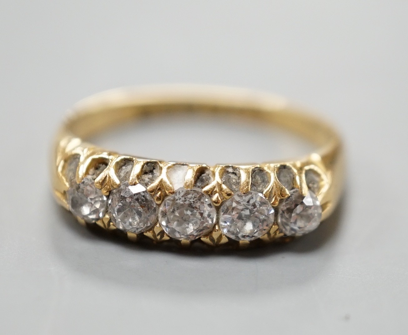 An early 20th century 18ct gold and graduated five stone diamond set half hoop ring, size N/O, gross weight 3.7 grams.